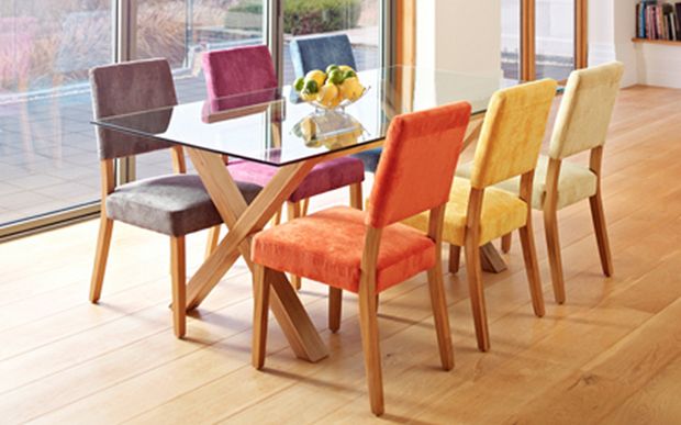 Different coloured dining chairs by a oak and glass dining table