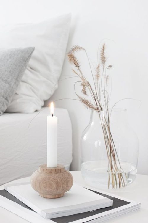 Nordic fall decoration with a wooden candle holder with candle, a clear vase and dried grasses is cool and simple