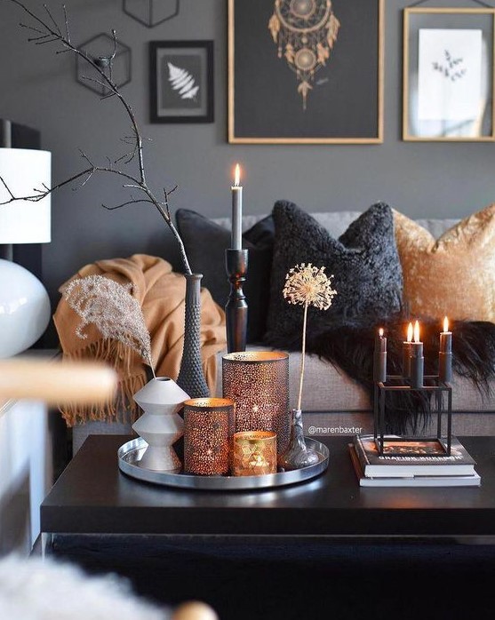 Nordic autumn living room in gray, black and orange, with candles, statement lanterns and a gallery wall and branches