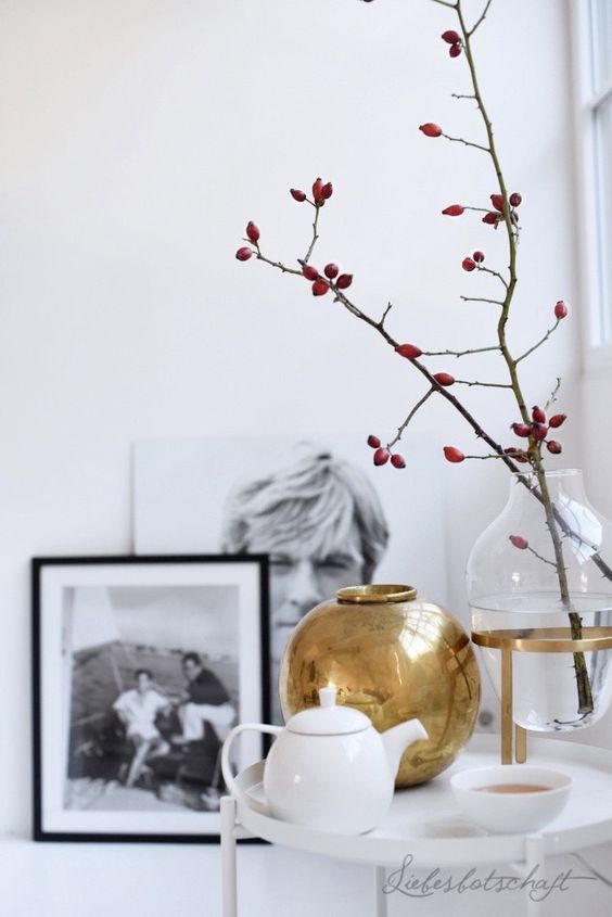 Scandinavian fall decor with a clear vase with branches, a gold vase and tea sets is a cool idea for any room