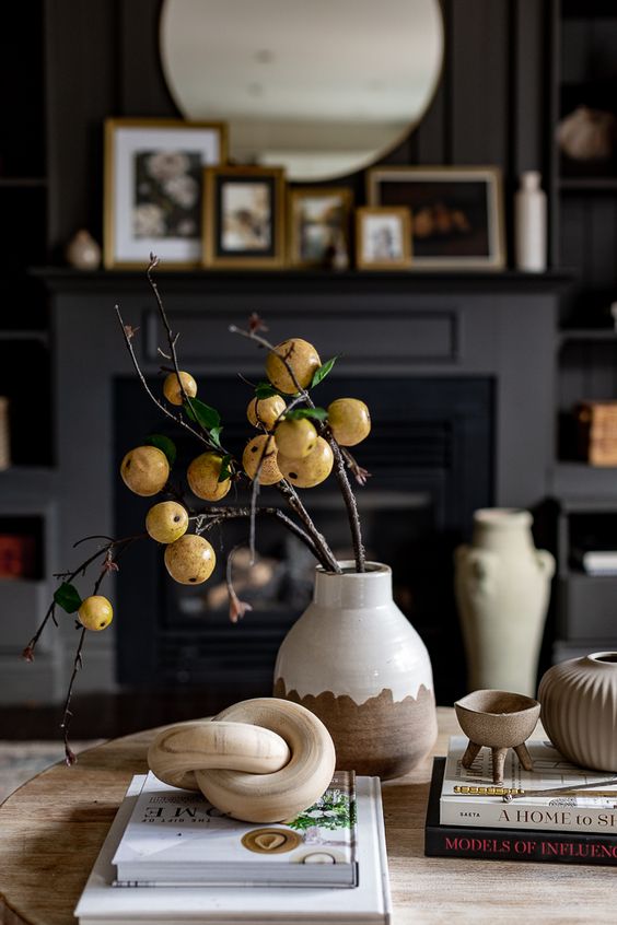 Scandinavian fall decor featuring a color block vase and branches with fruits, a wooden necklace and some bowls