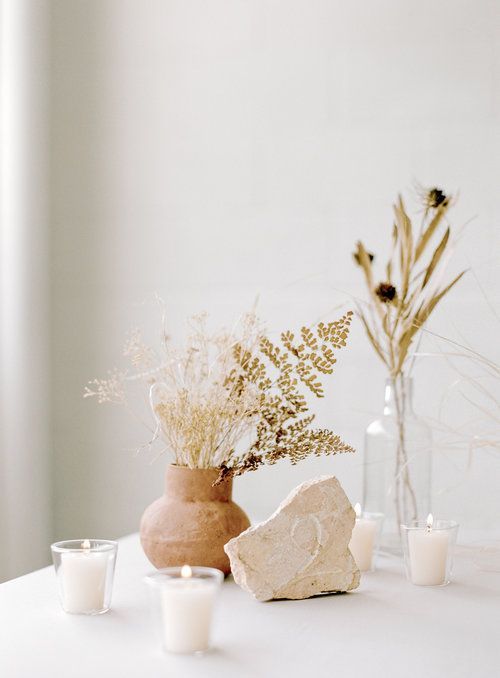 Scandinavian autumn decoration with stones, pillar candles, vases with dried flowers and grasses is cool and laconic