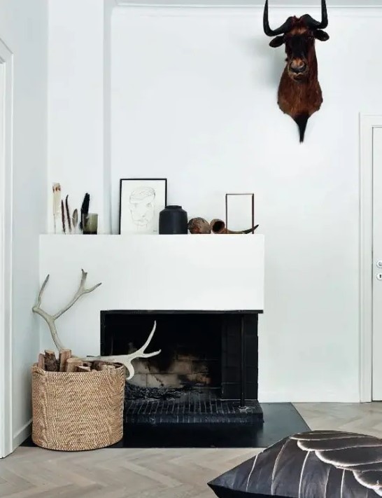 A basket of firewood and antlers and an artificial animal head on the wall for a simple and modern fall decoration