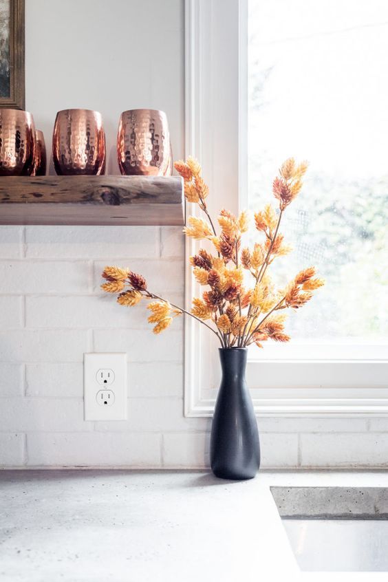 A black vase with dried branches is a cool idea for Scandinavian fall decoration