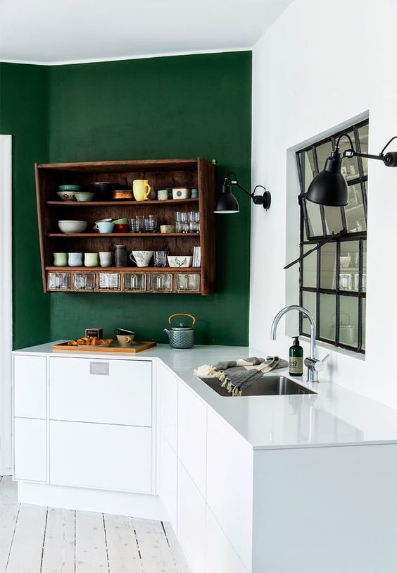 a catchy kitchen with green and white walls, white lower cabinets, a stained cabinet shelf and black lamps is cool and contrasting