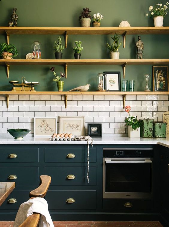 a catchy modern kitchen with green walls, whihte subway tiles and teal cabinets diluted with wooden shelves