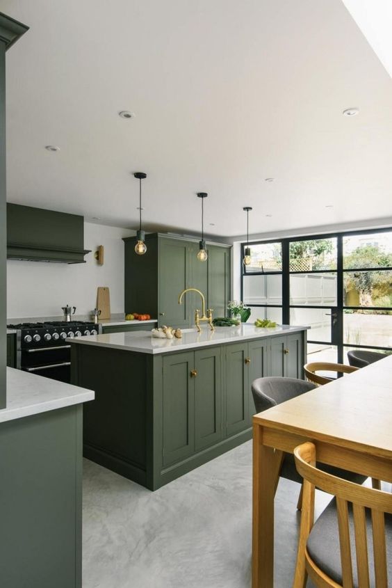a chic contemporary kitchen with green cabinets, white countertops, a black cooker and bulbs over the kitchen island