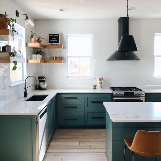 a contemporary kitchen with green cabinets, white tile walls, white stone countertops and black fixtures and lamps