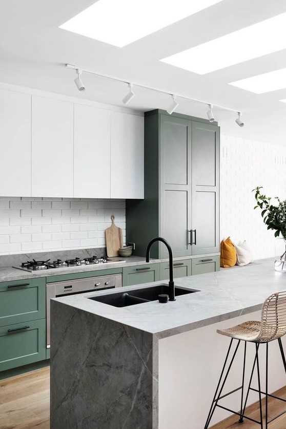 a cool kitchen with white and green cabinets, a grey stone kitchen island, a white tile backsplash and a black faucet
