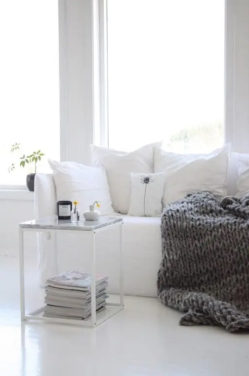 A cozy white corner jazzed up for fall with a thick knit blanket is a great Nordic-inspired idea