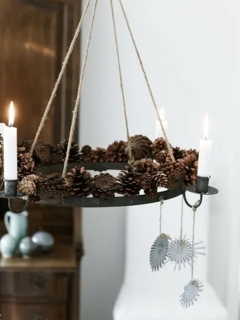 A creative pendant chandelier with pine cones and candles as well as hanging paper decorations for a natural feel