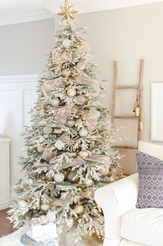 a delicate flocked Christmas tree with lights, mesh ribbon, snowflakes, silver ornaments is a very chic decoration
