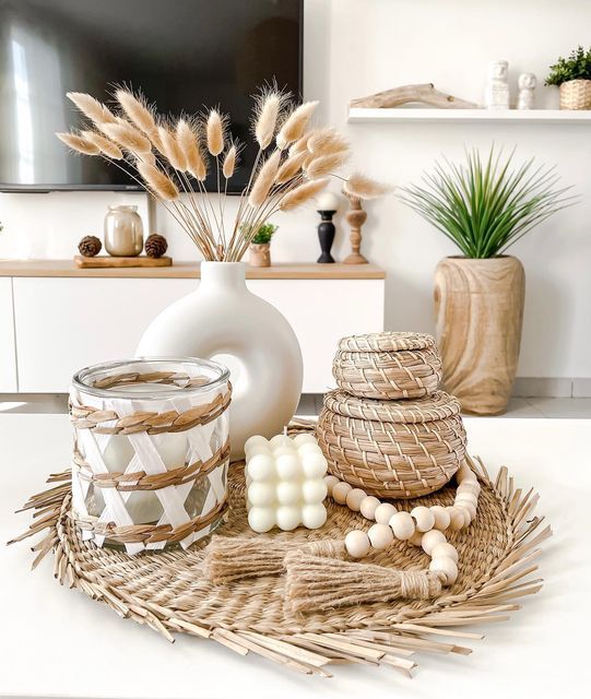 an autumnal Scandinavian arrangement with a woven tray, a candle, some woven mini boxes and a vase with bunny tails