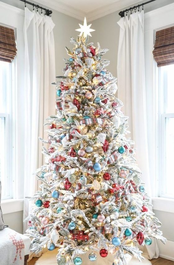 a flocked Christmas tree decorated with blue, pink, turquoise and metallic ornaments and lights plus plaid ribbons