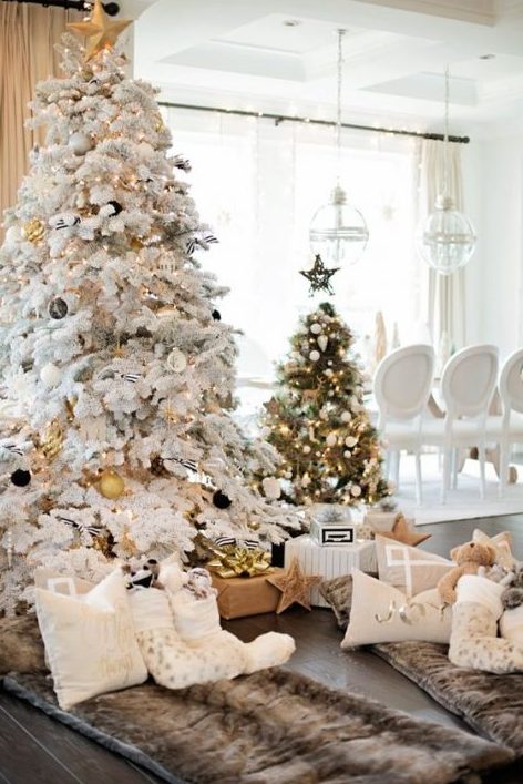 a flocked Christmas tree with black and gold ornaments and a usual one wtih black and white ornaments