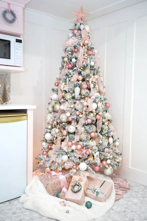 a flocked Christmas tree with pink, white and gold ornaments, pink ribbon and lights plus a pink star topper