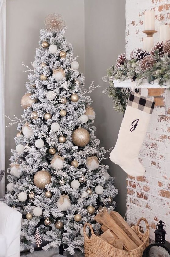 a flocked Christmas tree with white and metallic ornaments, twigs with berries and a tree topper is cool