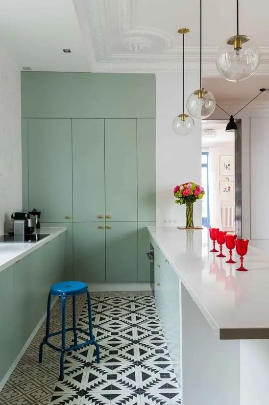 a minimalist mint green kitchen with a kitchen island, an electric blue stool, flat panel cabinets and pendant lamps