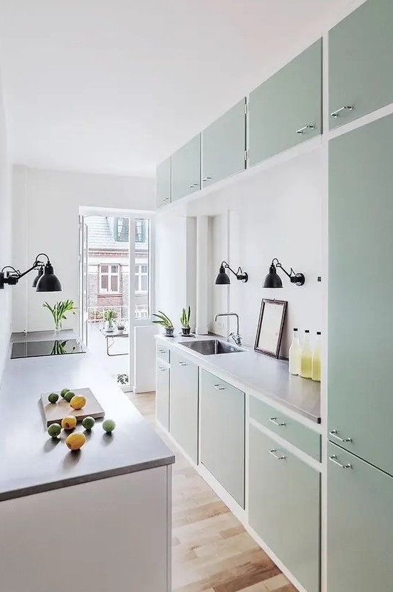 a mint green kitchen with flat panel cabinets, butcherblock countertops, black sconces is a stylish and chic space