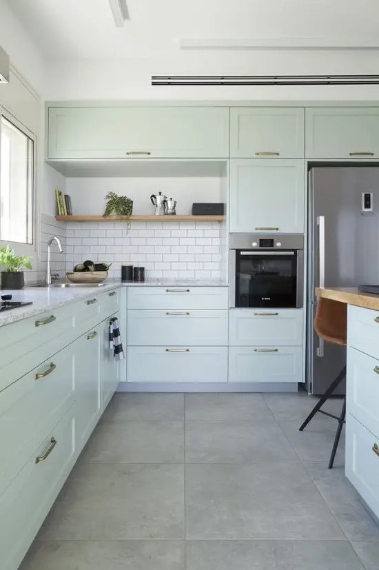 a mint kitchen with shaker cabinets, white stone countertops and a white subway tile backsplash plus a kitchen island