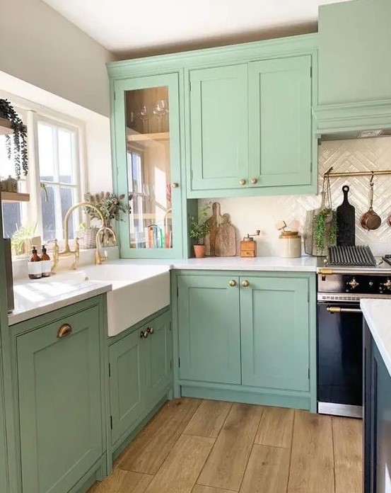 a mitn green kitchen with shaker cabinets, a creamy chevron tile backsplash, white countertops and a black kitchen island