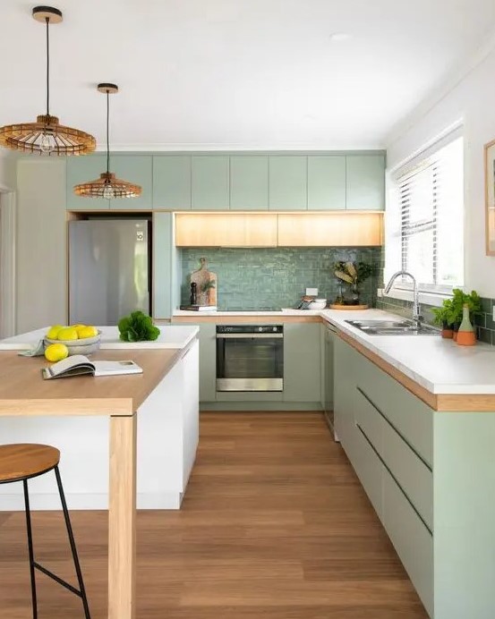 a modern pastel green kitchen with sleek cabinets, white stone countertops, a glossy green tile backsplash and woven pendant lamps