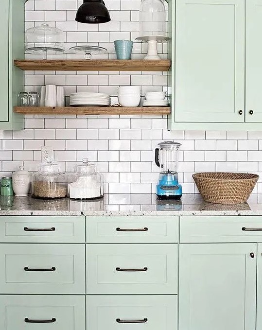 a modern sage green kitchen with chic cabinetry, a white subway tile backsplash with black grout and grey stone countertops
