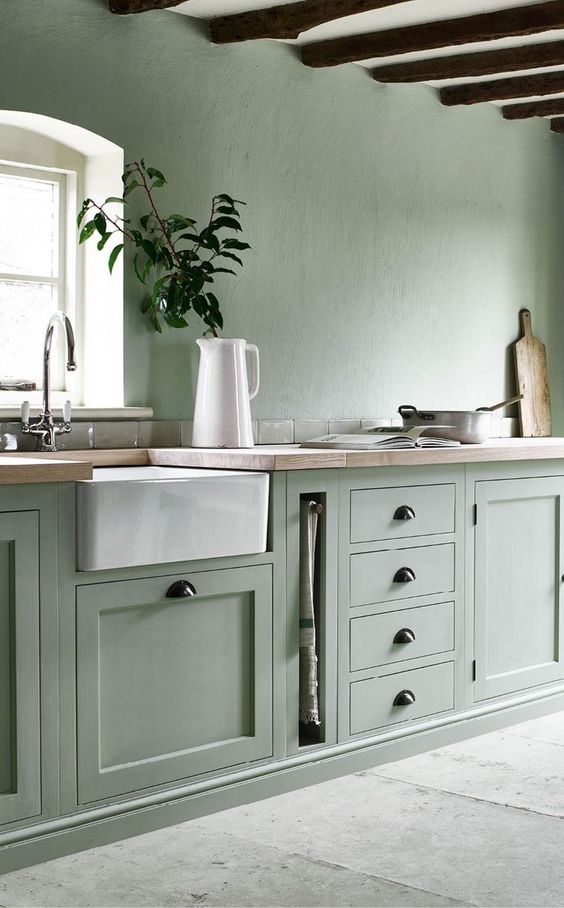 a pale green kitchen with a white ceiling and appliances plus black handles looks ethereal and very natural
