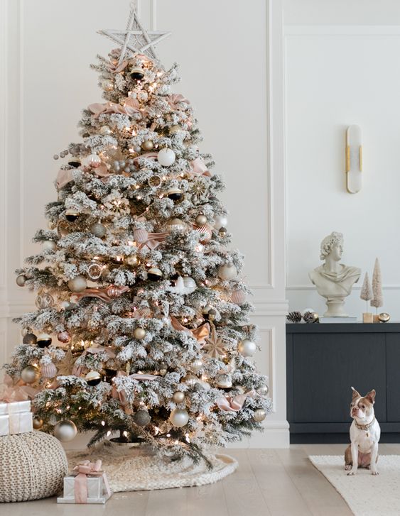 a refined flocked Christmas tree with metallic ornaments, blush ribbon, lights and a star topper is wow
