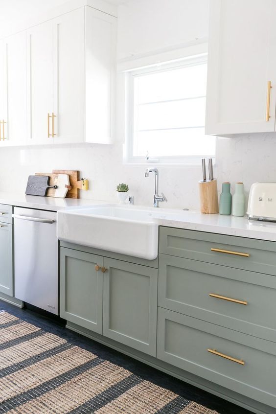 a seafoam green and white kitchen design with gold and brass hardware, with white countertops and printed rugs all over the kitchen
