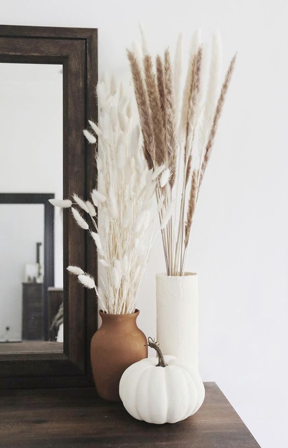 A stylish Scandinavian fall arrangement of vases, dried grasses and a white pumpkin is a cool idea for fall