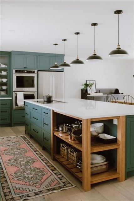 a traditional kitchen done in green, with white countertops, black lamps and a boho rug for a chic look