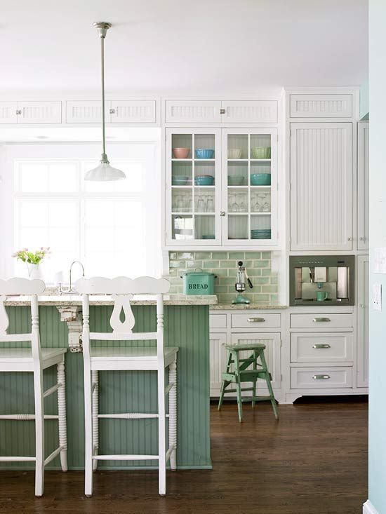 a traditional kitchen done with white cabinets and furniture, with a green kitchen island and tile backsplash for a touch of color
