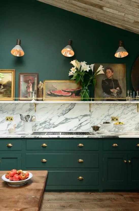 a vintage hunter green kitchen with a white marble backsplash and countertops, a shelf with artworks is chic