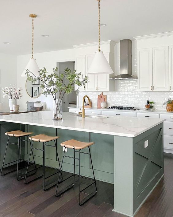 a white farmhouse kitchen with shaker style cabinets, an olive green kitchen island, white stone countertops and white pendant lamps