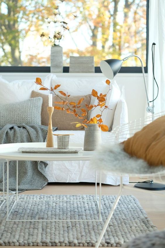 An airy Scandinavian fall decoration with bright leaves, candles and some vases is a cool solution for fall