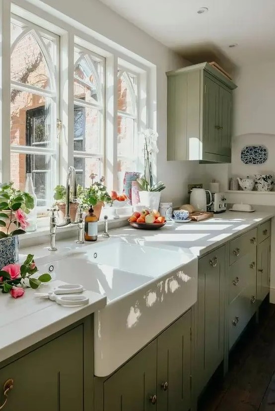 an elegant vintage sage green kitchen with white wooden countertops and a white backsplash, with neutral fixtures is a chic idea