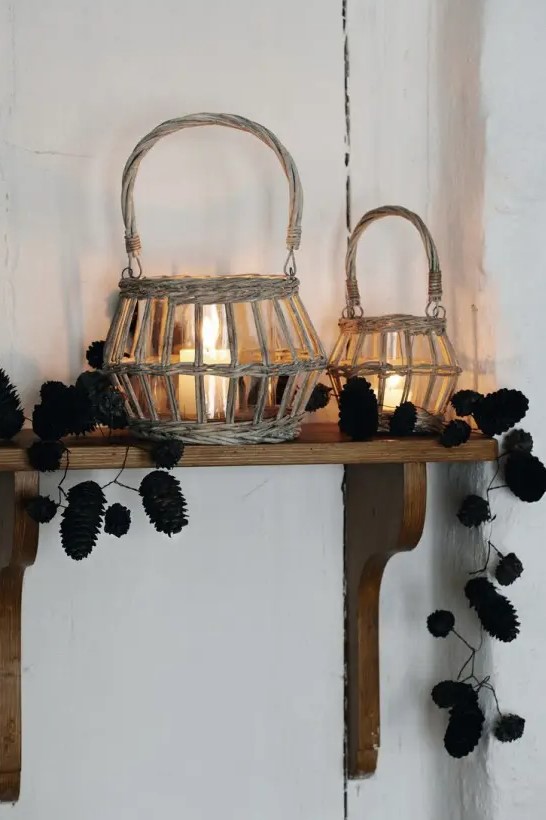 Candle lanterns in baskets and pine cone garlands on the shelf create a natural autumn feel