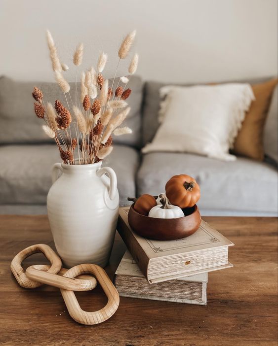 Elegant Scandinavian fall decor with wooden necklace, mini pumpkins and a jug of dried grasses