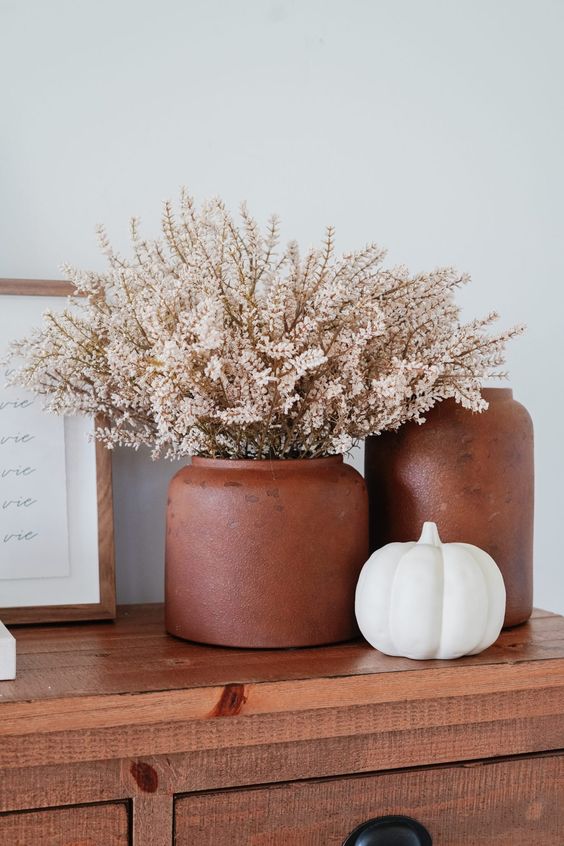 The elegant and laconic Scandinavian autumn decoration with terracotta vases and a white pumpkin is amazing