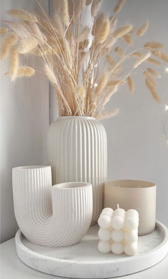 Elegant white Scandinavian fall decor with a tray, fluted vases with bunny tails, a candle in a glass and a pearl shaped glass