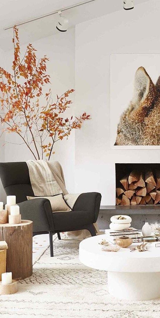 Simple Scandinavian living room with tree stumps and pillar candles, some autumn branches and a fox artwork