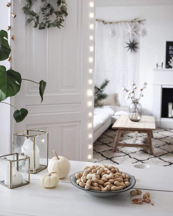 Simple Scandinavian fall decor with nuts on a plate, white pumpkins and candle lanterns is a cool solution