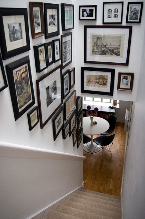 A striking gallery wall with photos and artwork in mismatched black and only dark-stained frames taking up two walls