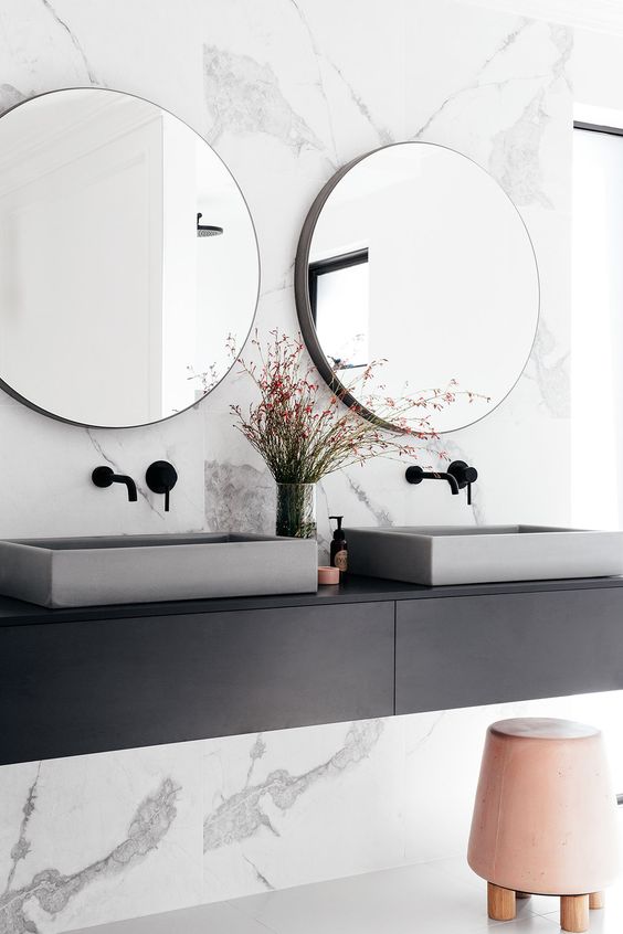 Concrete sinks and a pink leather ottoman add style to the bathroom