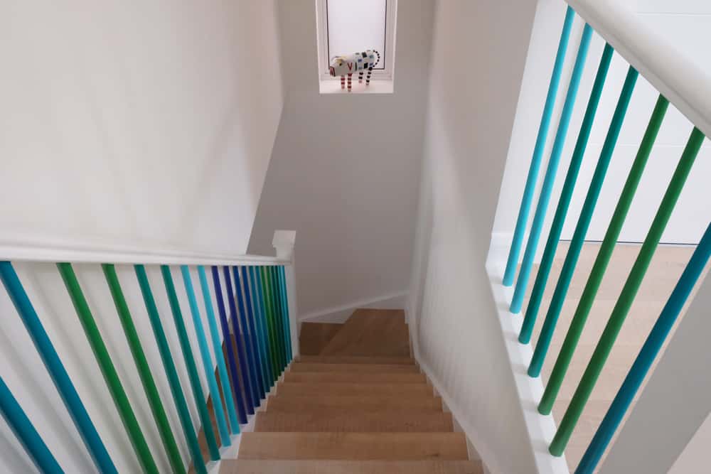 Narrow staircase with teal and purple railings