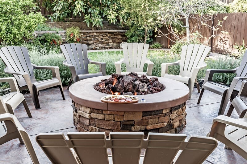 Round stone fire pit with plastic chairs 
