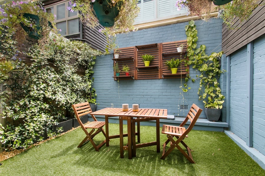 small backyard patio with grass and wooden table