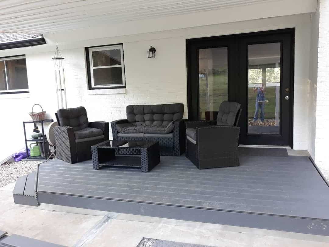 Small gray deck with black wicker furniture 