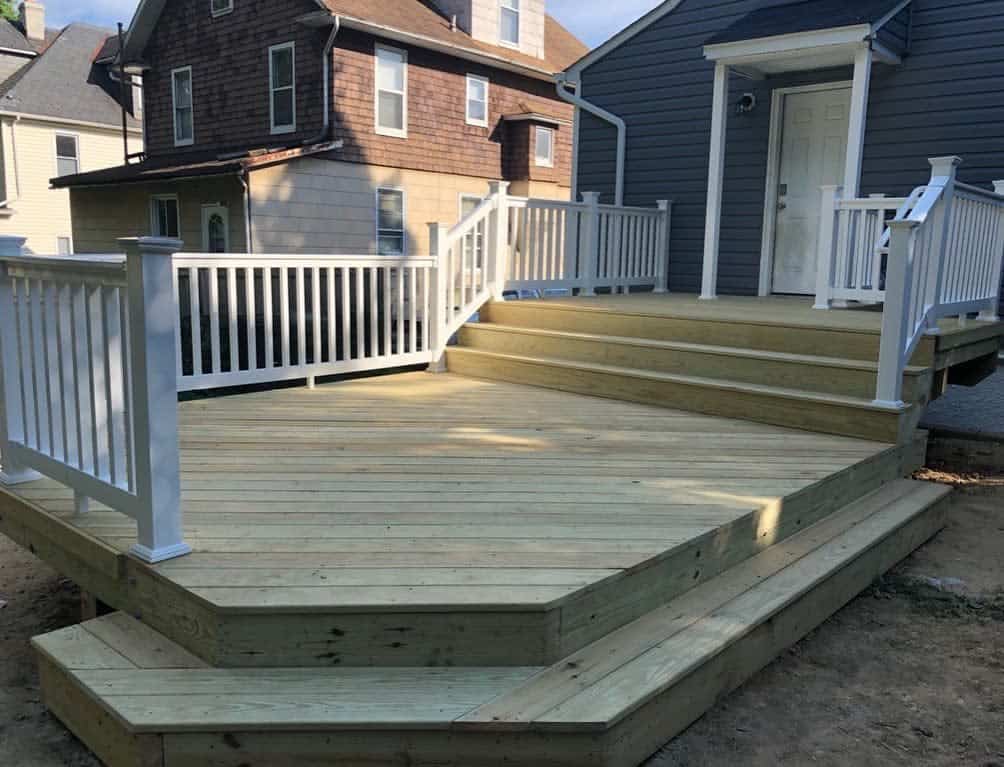 Large empty wooden patio in the backyard, white railing 